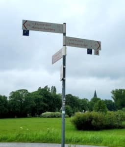 Wegweiser mit St. Gereon von Monheim im Hintergrund