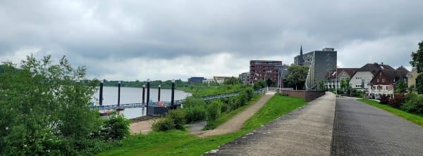 Rheinpromenade mit der Kirchturmspitze der Marienkapelle von Monheim im Hintergrund